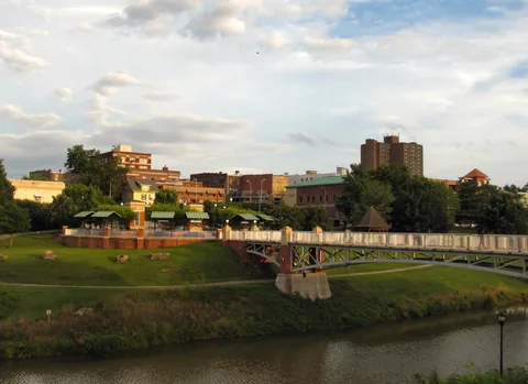 Downtown Maryville buildings beyond a footbridge over Pistol Creek, with a grassy greenway in front.
