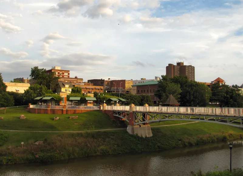 Downtown Maryville buildings beyond a footbridge over Pistol Creek, with a grassy greenway in front.