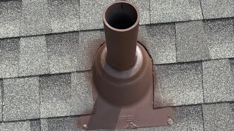 Brown painted pipe boot and vent pipe set into gray architectural shingles.